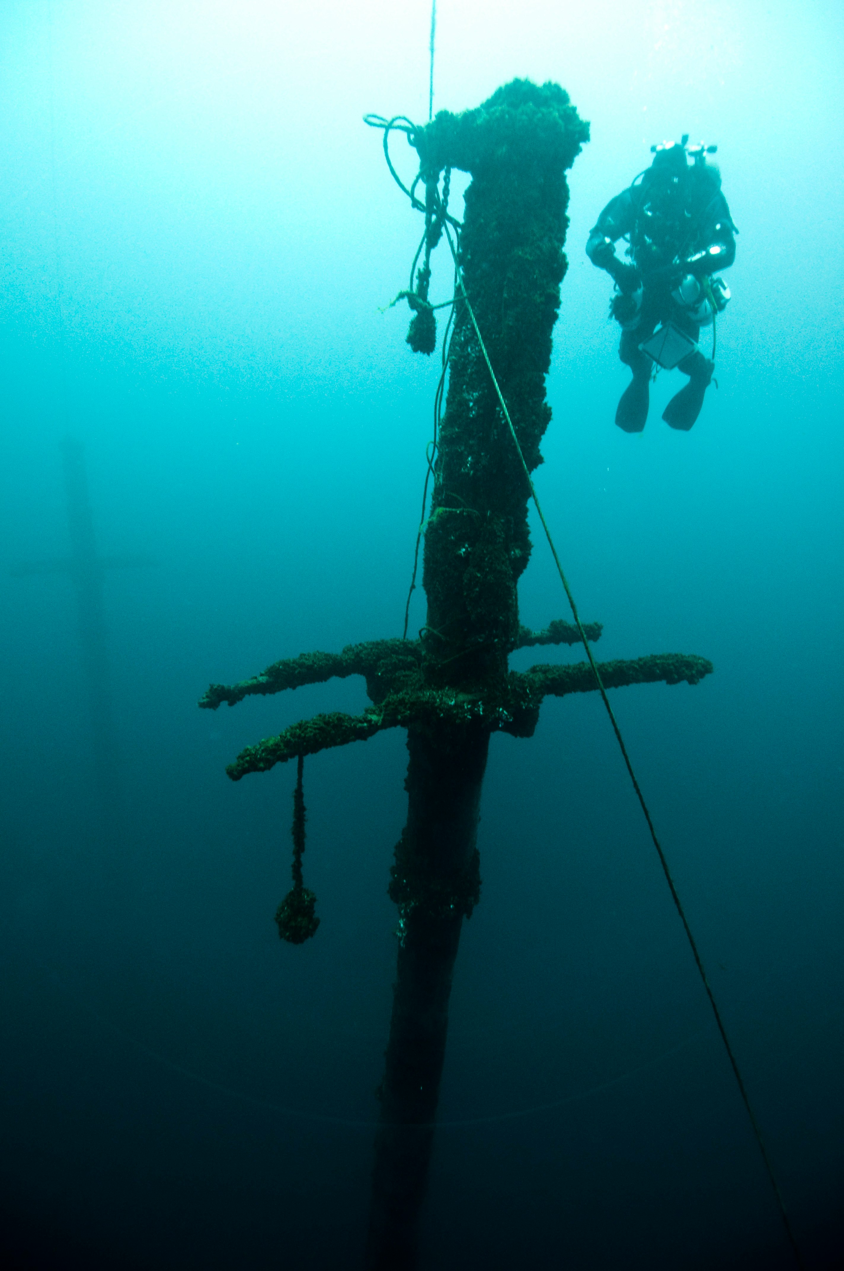 person wearing diving suit near sunken ship